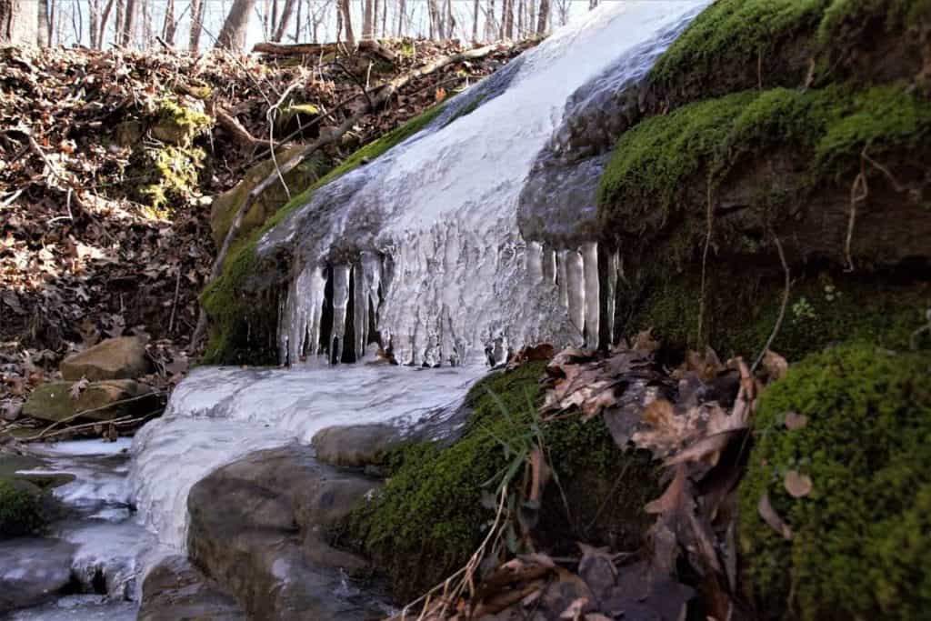 Frozen waterfall over green moss covered rocks